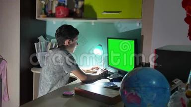 绿色钥匙室内青少年男孩玩电脑特写手游视频后坐.. 这个男孩在电脑上工作